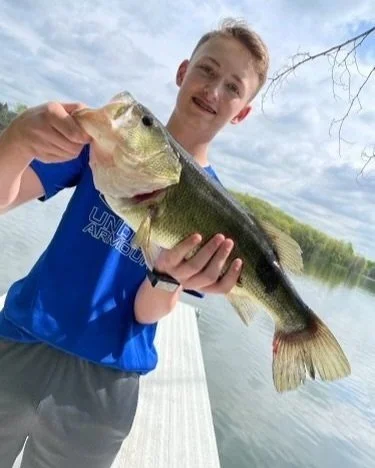 A guest on the dock holding up a largemouth bass