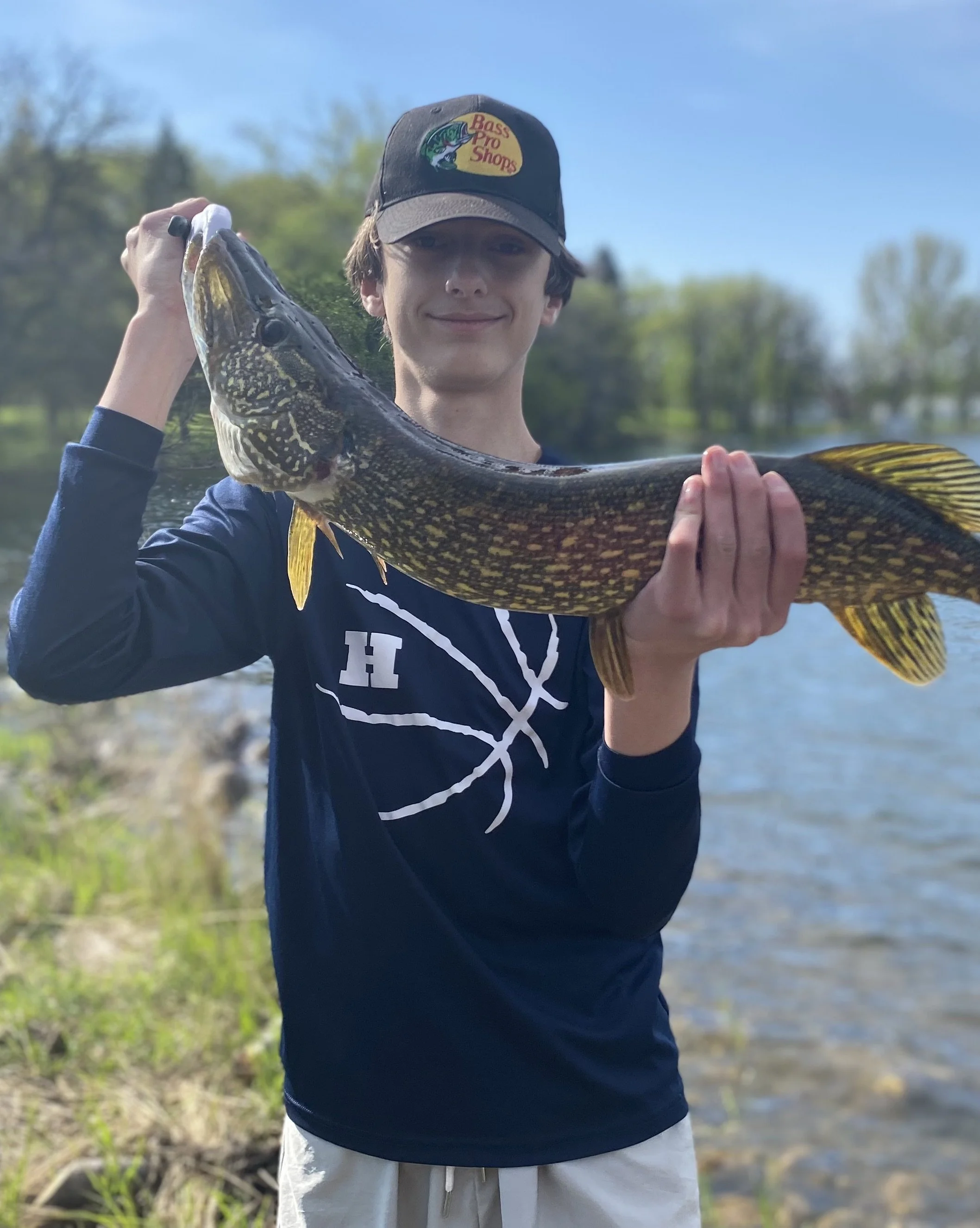A guest holding up a northern pike caught off the shoreline